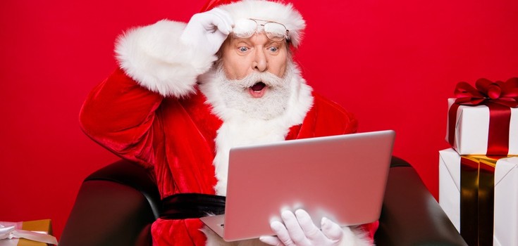 Père-Noël étonné devant son ordinateur portable.